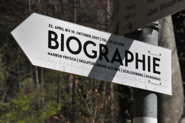 Der Vorarlberger Künstler Marbod Fritsch vor seiner Ring-Skulptur „Biographie“. Kleines Bild: Ein Hinweisschild führt zum Kunstwerk. Wolfgang Ölz