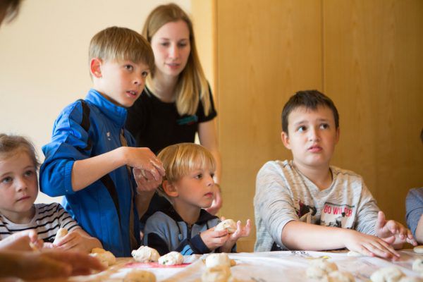 Oben: Den kleinen Bäckern wird gezeigt, wie Teig hergestellt wird. Rechts: Laureen (7) will den klebrigen Teig loswerden. Hartinger