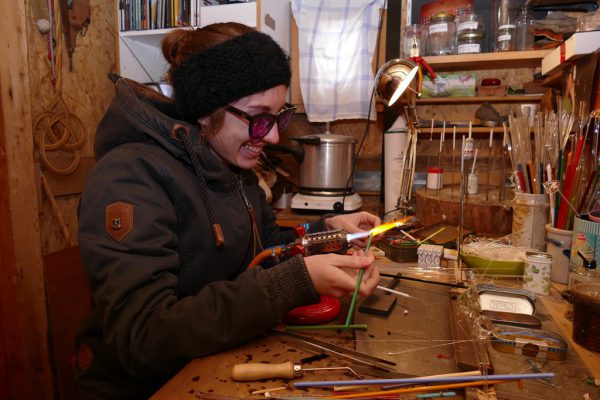 Anna Bertle trägt bei der Arbeit eine Schutzbrille (o.). Damit erkennt sie in der Flamme, wie heiß das Glas ist.