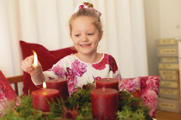 Ella zündet das erste Kerzchen auf ihrem Adventkranz an. Hartinger