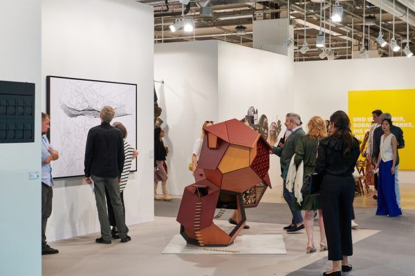 Blick in die diesjährige Art Basel (links), eine Besucherin fotografiert ein Objekt am Stand von Hauser und Wirth (oben) und Ausschnitt aus Adel Abdessemeds Videoarbeit (unten).Art Basel/Monsef, Art Basel/ Minjolle, Ölz