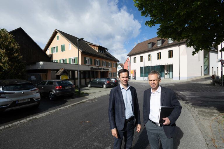 Bürgermeis­ter Florian Themeßl-Huber (l.) und Primus-Geschäftsführer Beat Fleisch vor der alten „Krone“, die im kommenden Jahr abgerissen und durch zwei Neubauten ersetzt werden soll. Unten v.l.:Derzeitige Situation sowie ein Modell und Pläne zum Siegerprojekt.Hartinger (2), Atelier Ender