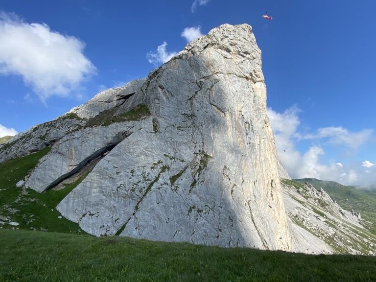 Der Verletzte und sein Begleiter wurden von der Hubschrauber-Crew direkt aus der Wand gerettet. Das Seil am Helikopter wurde dafür von 90 auf 135 Meter verlängert. Rot markiert im Bild der Helikopter (oben) und der Retter und Gerettete am Seil (unten)rega (2)