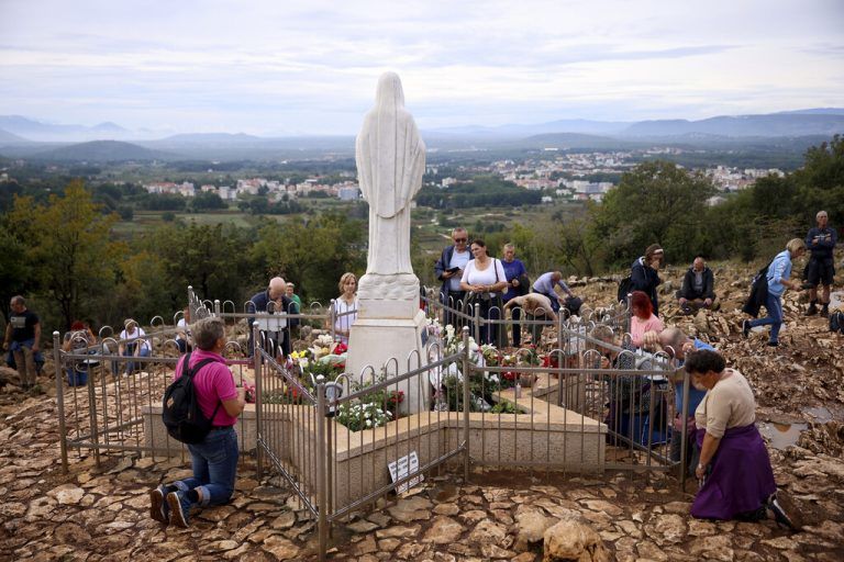 Pilger in Medjugorje vor einer Marienstatue. ⇒ap/durgut