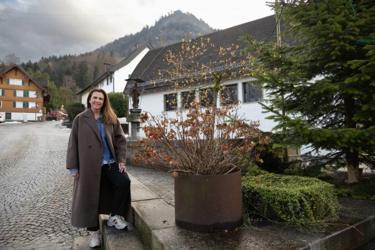 Karin Feurstein-Pichler vor dem Brunnen in Mühlebach. Im Hintergrund ihr Hausberg, der Karren.