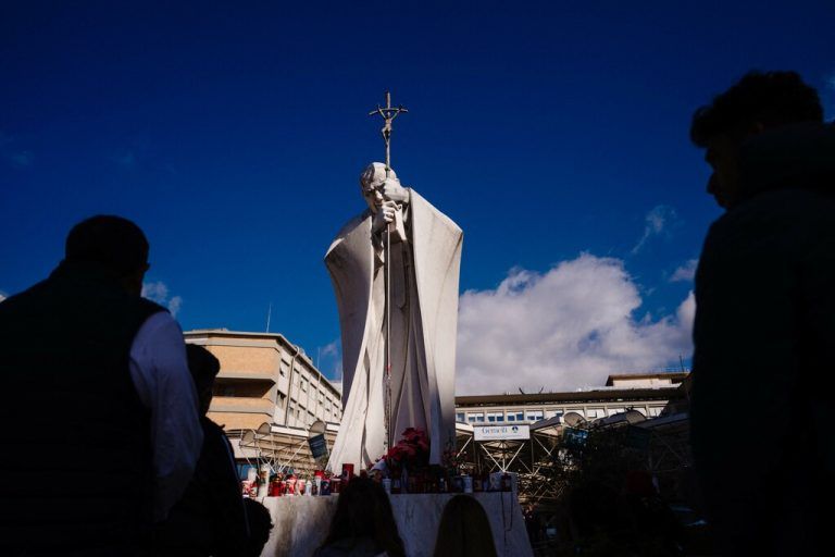 Gläubige legen seit Tagen Kerzen und Blumen an der Statue von Papst Johannes Paul II. vor der Klinik nieder und beten für Franziskus. ⇒APA
