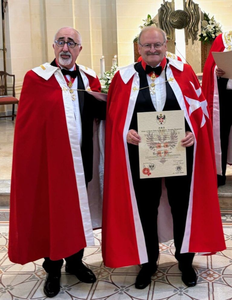 Stolz präsentiert Hubert Gorbach, flankiert von Grand Commander Noel Vassallo, im roten Mantel der Malteser seine Urkunde, die ihn fortan zum Ritter macht. ⇒PRIVAT